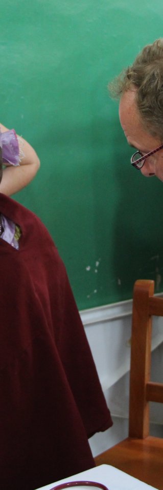 En manlig läkare konverserar med ett barn, ärrat av noma.