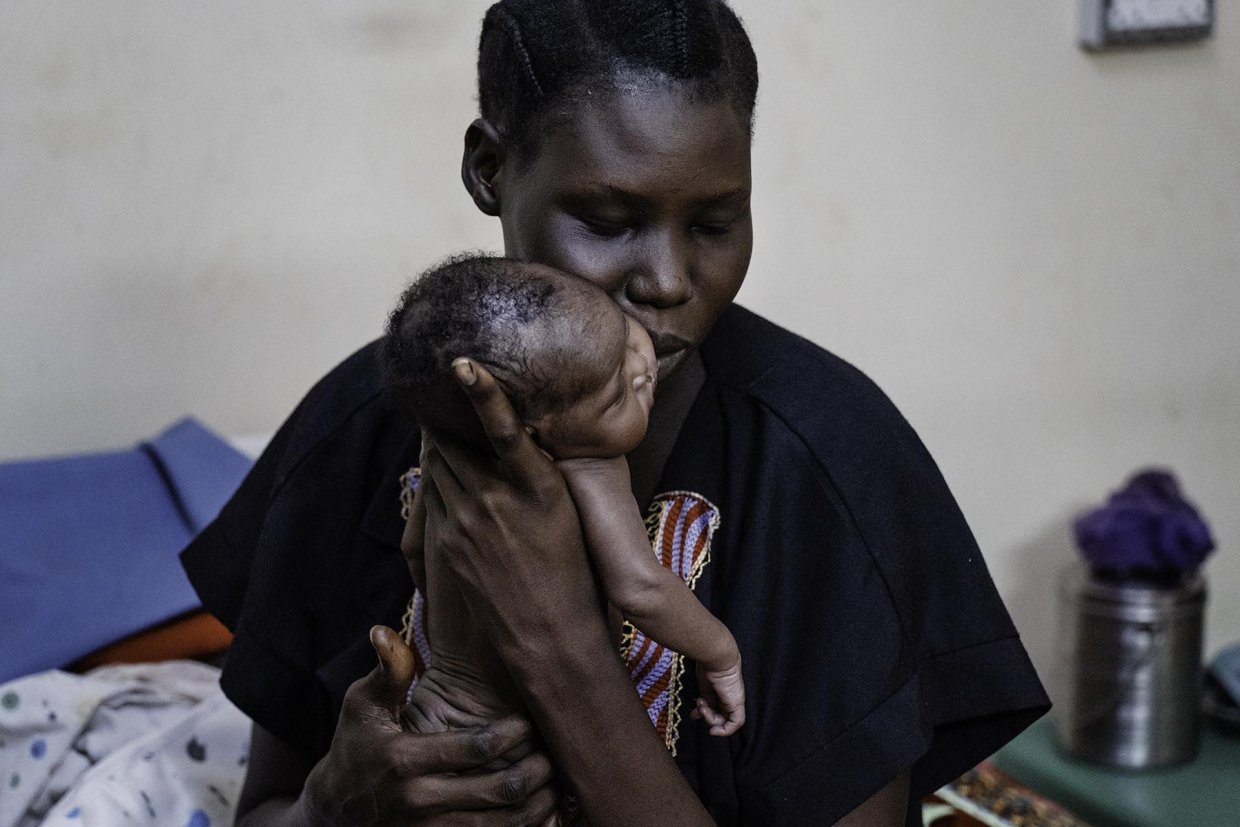 en kvinna håller sitt nyfödda barn mot kinden