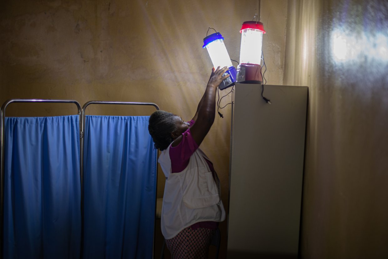 En kvinna sträcker sig för att fixa till lampor ovanpå ett skåp.