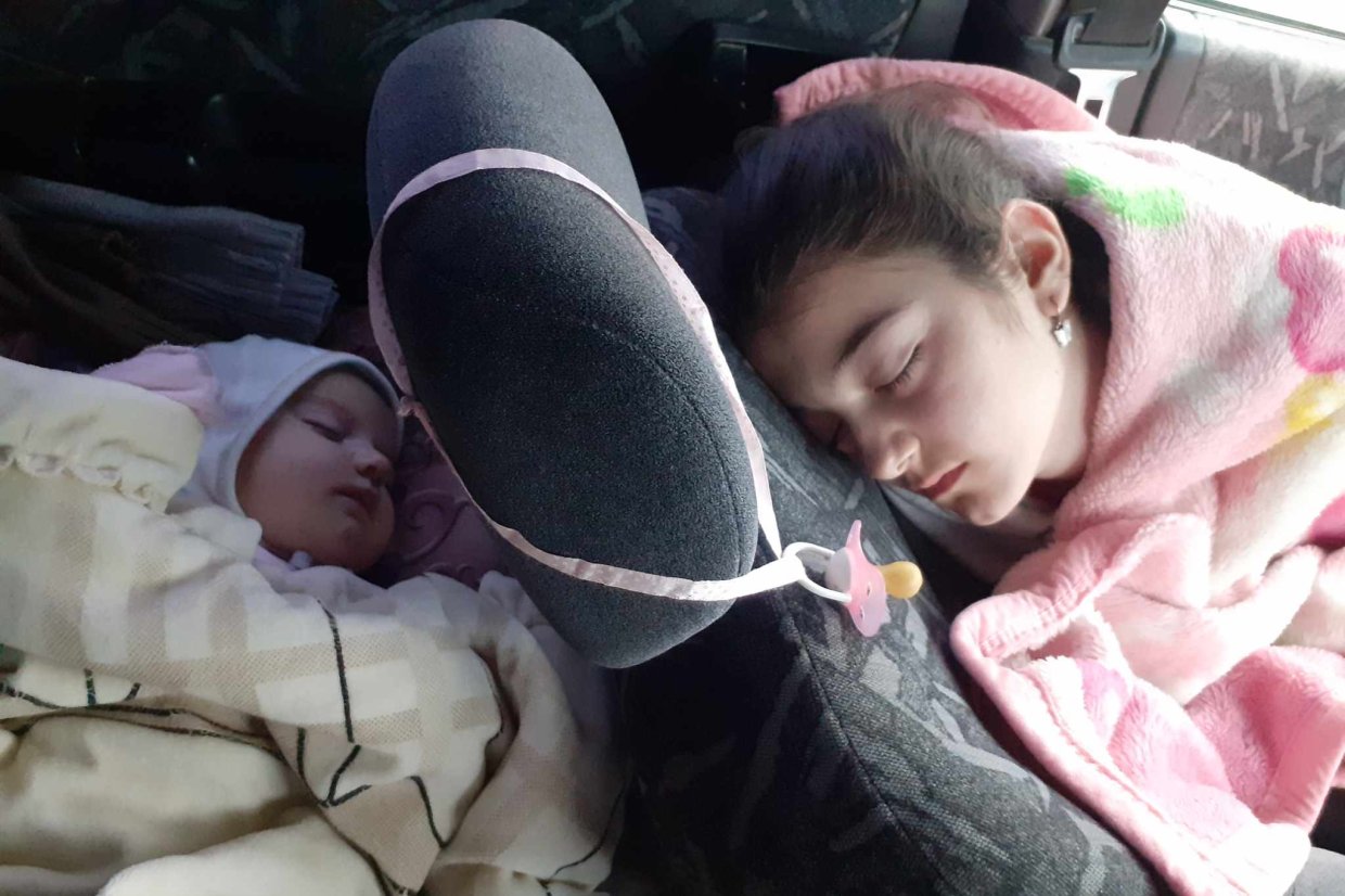 En bebis och en tonåring sover i en bil under filtar.