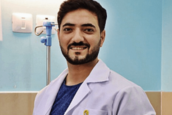 En man iklädd i en läkarrock från Läkare Utan Gränser ler och kollar in i kameran.