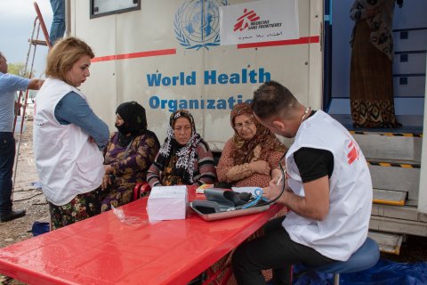 Tre patienter får vård av två läkare framför vår mobila klinik