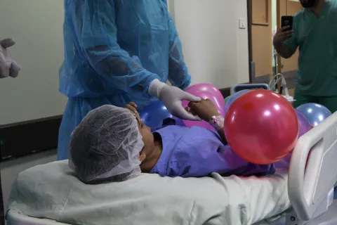 Salwa ligger på en bår med ballonger på sig