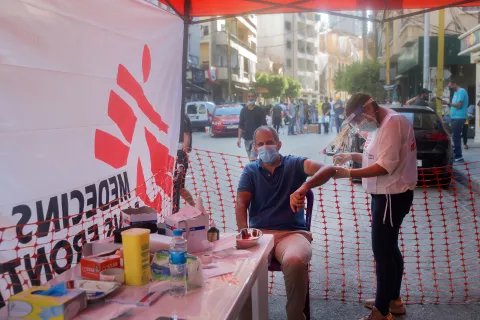 En man sitter på en stol och får vård vid en mobil klinik efter explosionen i Beirut, Libanon.