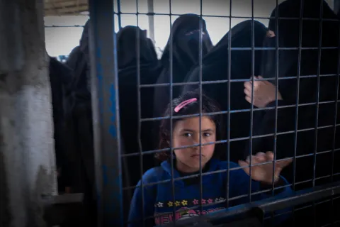 En flicka som bor i lägret Al-Hol i Syrien tittar genom ett stängsel.