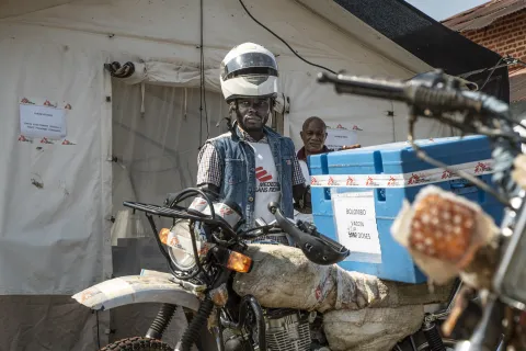 En man står vid en motorcykel vid en vaccinationskampanj mot mässling i Kongo-Kinshasa.