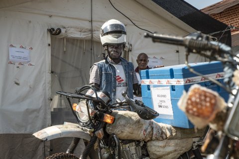 En man står vid en motorcykel vid en vaccinationskampanj mot mässling i Kongo-Kinshasa.