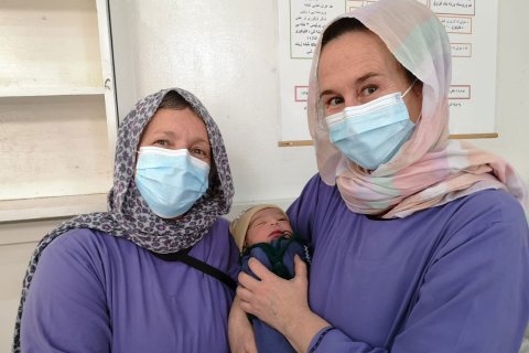 Barnmorskorna Astrid och Lena håller i en nyfödd bebis, på Khost kvinnorsjukhus i Afganistan.