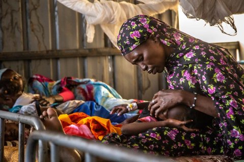 Rauda Adam Isa klappar sin dotter på pannan i en sjukhussäng på sjukhuset El Fasher, norra Darfur, Sudan.