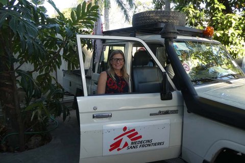 Sjuksköterskan Ulli Hedberg, som är i Haiti, står bakom en bildörr och tittar in i kameran.