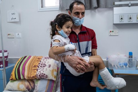 Fembarnspappan Mohammed Aboud bär sin fyra år gamla dotter Hala som har gips på höger fot, på al-Awda sjukhus i norra Gaza, Palestina. 