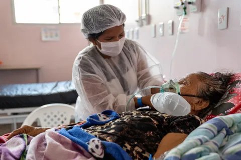 Sjukvårdspersonal hjälper 109-åriga Bonifácia de Oliveira med andningen. Bonifácia ligger i en säng där hon vårdas för covid-19 på ett sjukhus i Brasilien där Läkare Utan Gränser jobbar för att stötta covidinsatsen i Amazonasregionen