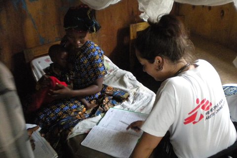 Läkaren Jennifer Turnbull sitter på en säng på Mweso sjukhus i Kongo-Kinshasa. På andra sidan sängen sitter en mamma med sitt lilla barn.