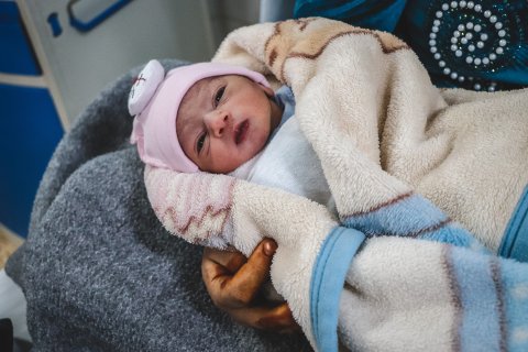 Bebisen Layth ligger på sin mammas arm på mödravårdsmottagningen al-Amal i Mosul, Irak.
