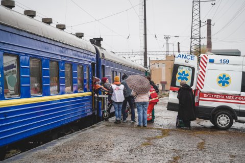 En patient som ligger på en bår förs över från ett tåg till en ambulans i Lviv, Ukraina. 