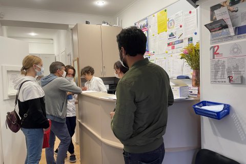 Personer står i kö vid receptionen på en vårdcentral