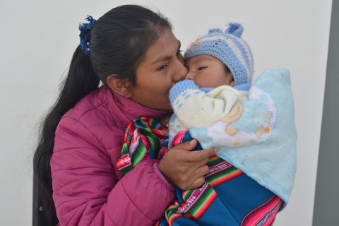 Mamma pussar sitt barn på kinden.