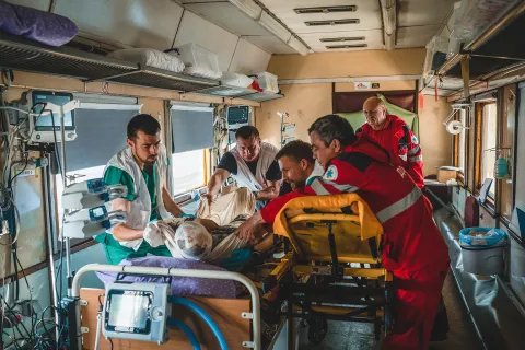 I en tågvagn flyttar Läkare Utan Gränsers personal en patient från en bår till en säng.