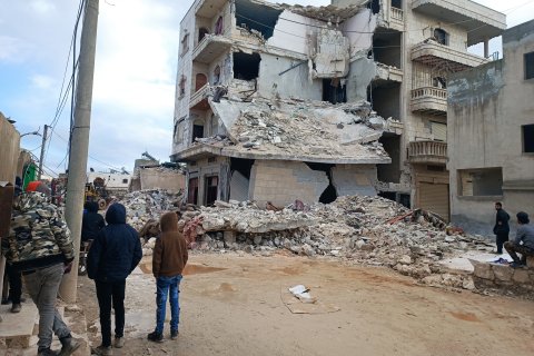 Några personer står framför ett hus som nästan helt har förstörts efter måndagens jordbävning.