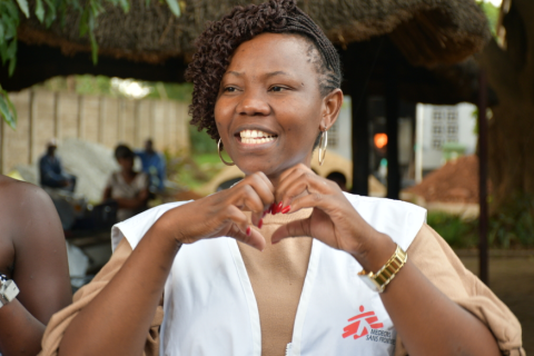 En ung kvinna med MSF-väst gör ett hjärta med händerna