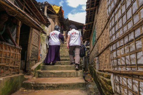 Två medarbetare med Läkare Utan Gränsers logga på ryggarna går upp för en trappa i Cox's Bazar.
