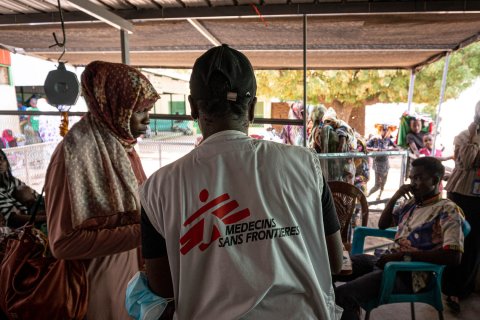 Man med Läkare Utan Gränser väst visar en blankett för en kvinna till vänster om honom