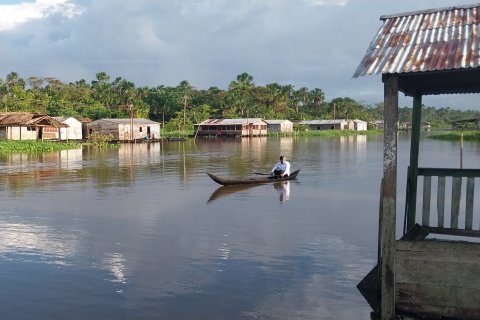 En flod med några enkla träbyggnader i bakgrunden.