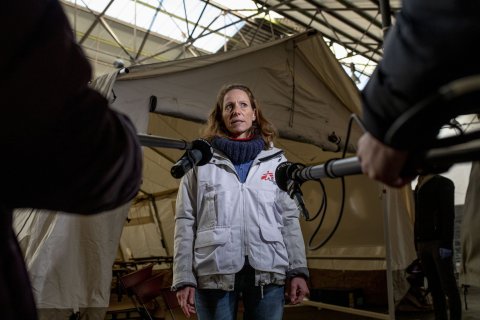 Kvinna i Läkare Utan Gränser-kläder blir intervjuad med två mikrofoner riktad mot sig.