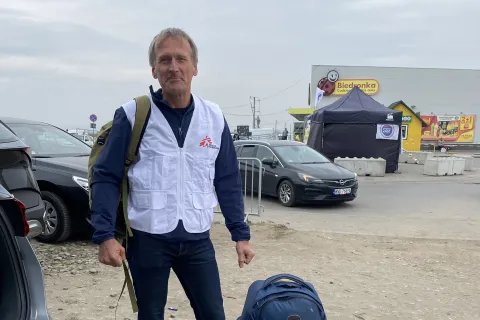 En man med Läakre Utan Gränser väst står bredvid två fullpackade väskor.