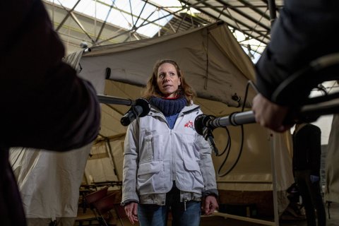 En anställd på Läkare Utan Gränser blir intervjuad av TV framför ett sjukvårdstält