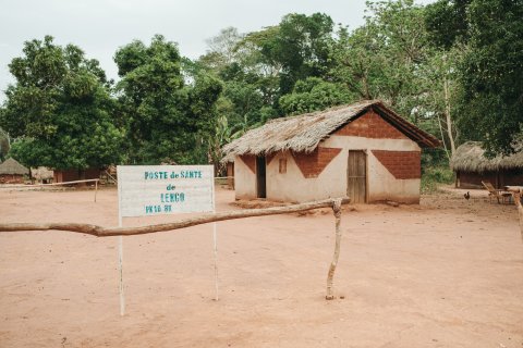 Ett litet hus byggt av tegelstenar syns bakom en vit skylt i ett stepplandskap