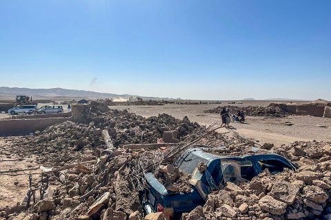 fullständigt raserade hus och en bil täckt av tegelstenar 