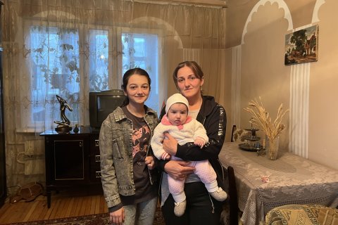 Porträttbild på en mamma med sitt tonårsbarn och sin bebis. 