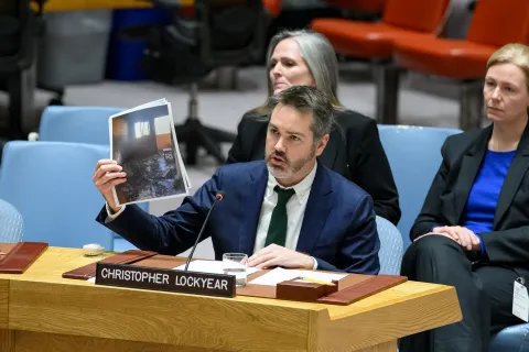Man i kostym håller upp bilder.