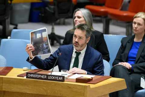 Man i kostym håller upp bilder.