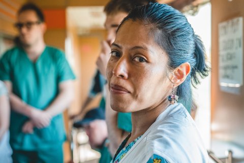 Kvinna från Läkare Utan Gränser tittar in mot kameran och ler, i bakgrunden står mer personal.