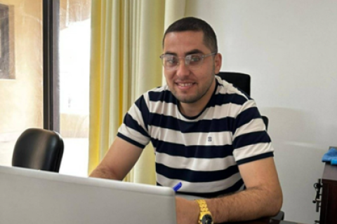 Man med randig t-shirt sitter vid skrivbord.