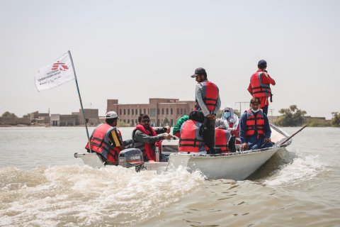 En båt med personal från Läkare Utan Gränser och dess flagga längst bak åker fram i ett översvämmat landskap.