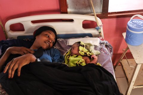 en kvinnar och hennes nyfödda barn ligger i en sjukhussäng