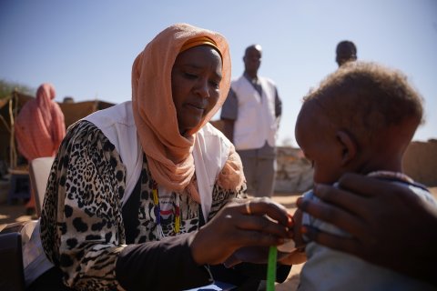 en kvinnlig sjukvårdare mäter ett barns överarm med en remsa i olika färger