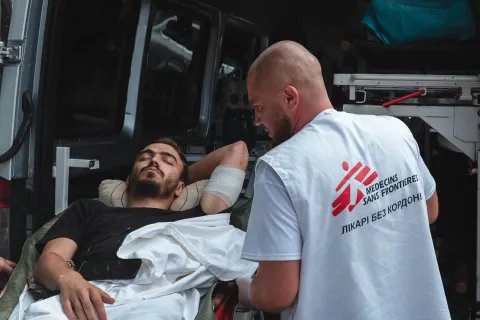 Man liggandes på bår i ambulans vårdad av sjukvårdare i Läkare Utan Gränsers väst