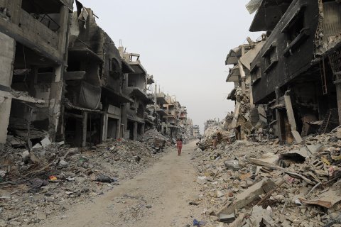 Barn på en gata med sönderbombade hus