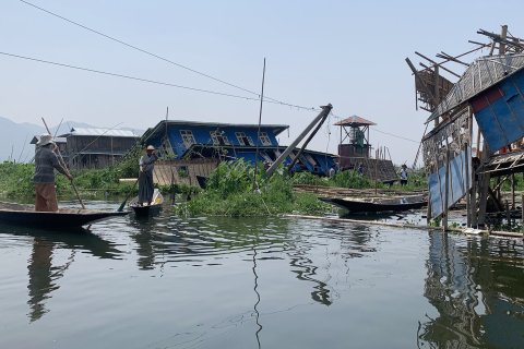 Två män i varsin båt tar sig mellan raserade hus