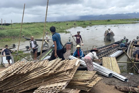 En grupp människor lastar bambupaneler på båtar