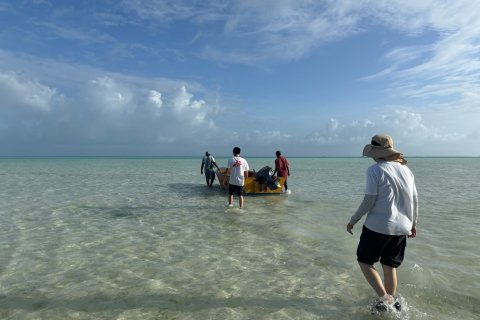 En båt ute på runt vatten med människor på väg mot båten. En med Läkare Utan Gränser-tröja.