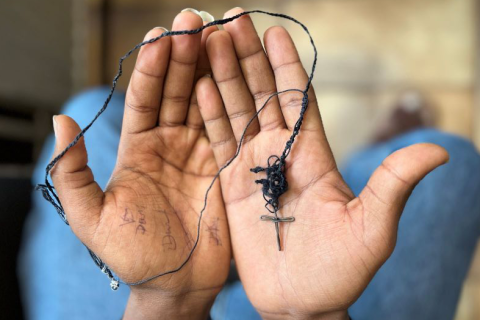 Ett halsband med ett kors i öppna handflator.