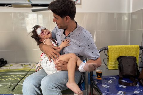 Man med sitt skadade barn i famnen på ett sjukhus i Gaza