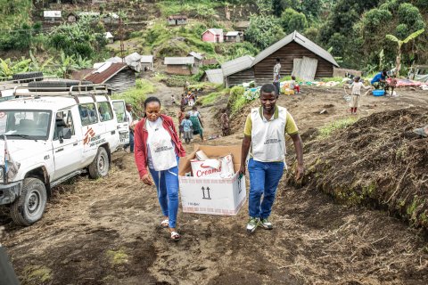 Två personer bär en kartong med material