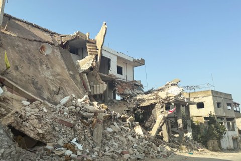 Ett förstört hus med högar av bråte framför.