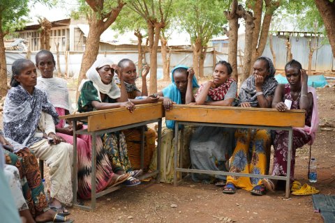 En grupp kvinnor sitter vid ett avlångt bord utomhus.